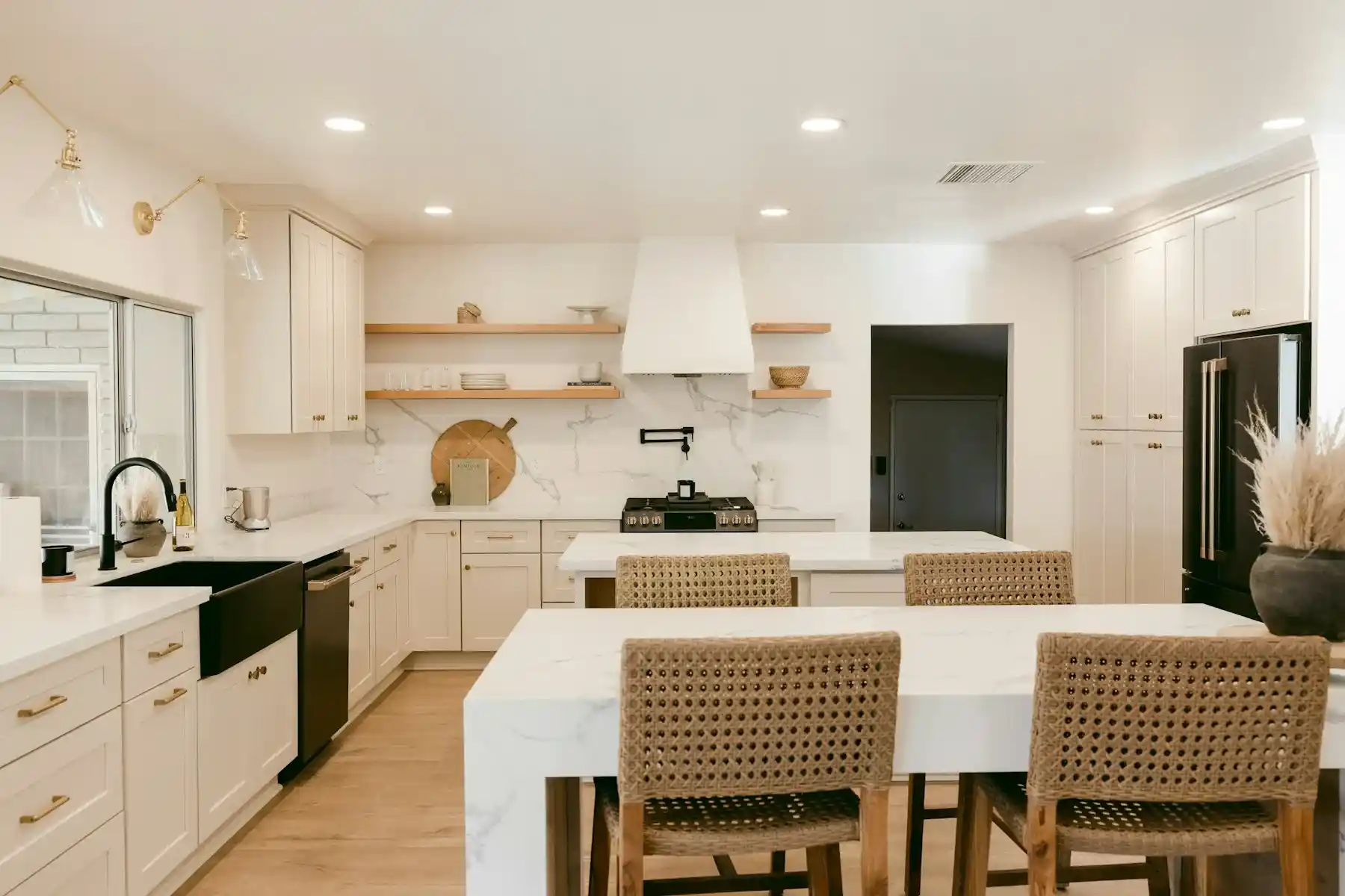 A bright kitchen with an island, woven stools and white cabinetry