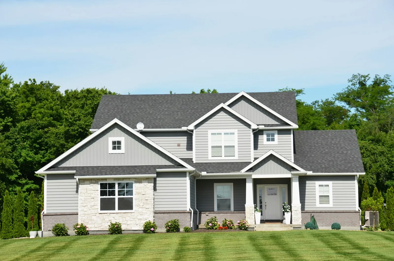 A two-story suburban home with stone and siding, seen from the front lawn